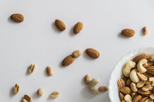A white bowl filled with a variety of nuts sitting on top of a table