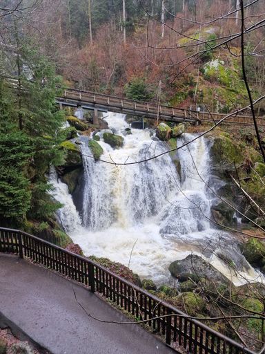 A scenic landscape of a bridge arching over a small waterfall