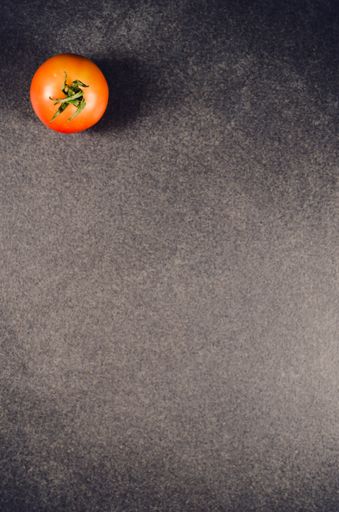 A vertical top view of a ripe cherry tomato isolated on a black background