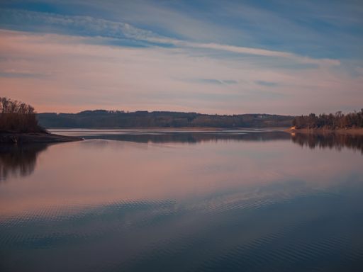 Here you see a beautiful sunset at a blue lake with some clouds in the air