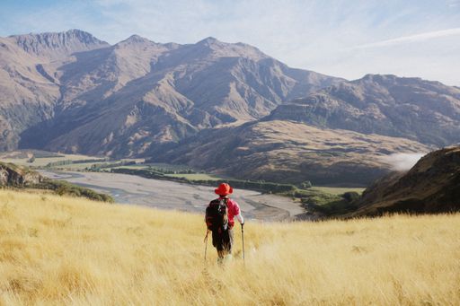 The hiker standing in the field and enjoying the view of mountains.