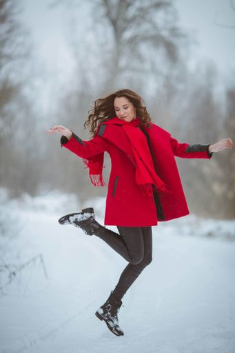 A vertical shallow focus shot of a female wearing a red coat and enjoying the snow