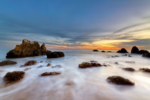 A landscape of the sea with long exposure surrounded by rocks during a beautiful sunrise