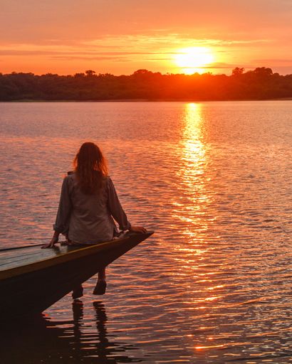 A vertical shot of a female sitting on a pier enjoying the view at sunset