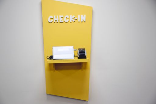 A yellow automated check-in machine mounted on a wall.