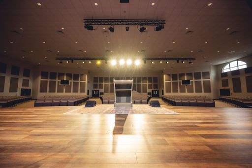 An illuminated empty hall with a stage and empty seats.