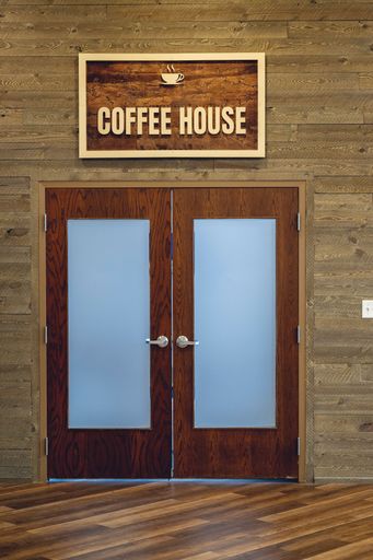 The frosted wooden doors with a sign above them. Coffee House.