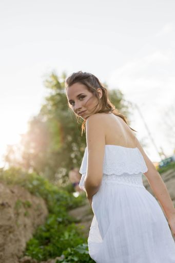 A vertical shot of a young blonde with a white shirt walking outside captured from her back