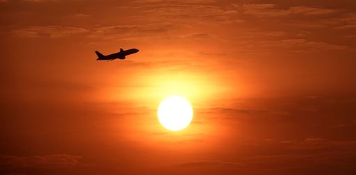 a Plane flying against a bright sunset