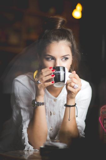 A Cheerful young successful Bosnian female with brown hair looking away while having coffee