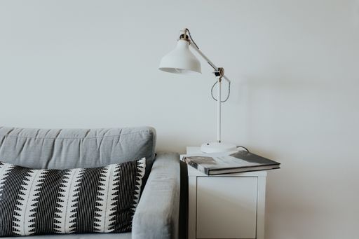 A comfortable couch in modern house with a lamp on a little white shelf and a book with a waterfall on it