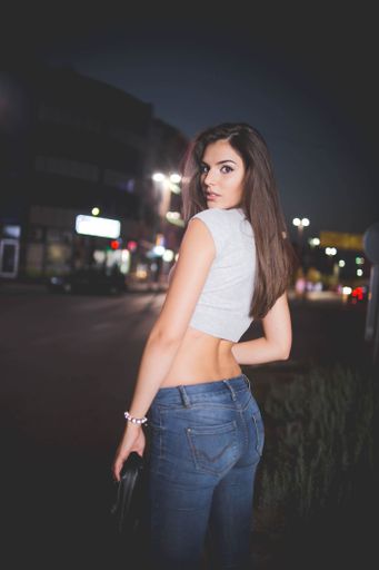 A young attractive lady with crop top and low waisted jeans posing in the street