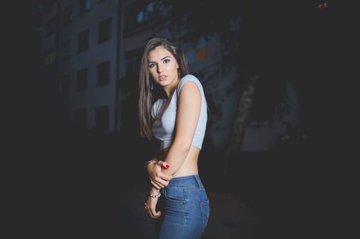 A young attractive lady with crop top and low waisted jeans posing in the street