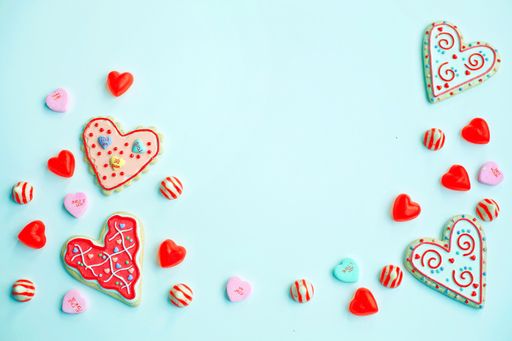 A composition of homemade heart-shaped decorated cookies and sweet candies on a light blue background with copy space