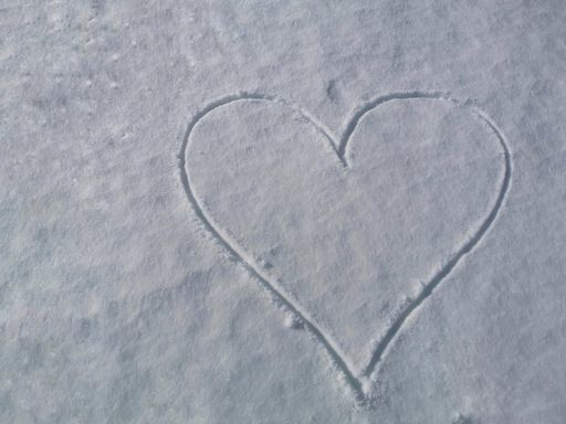 A closeup top view of a simple heart drawn on a snow surface