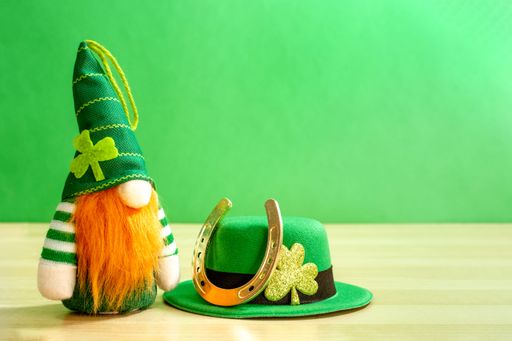 A funny gnome leprechaun, horseshoe, and green hat on a wooden table