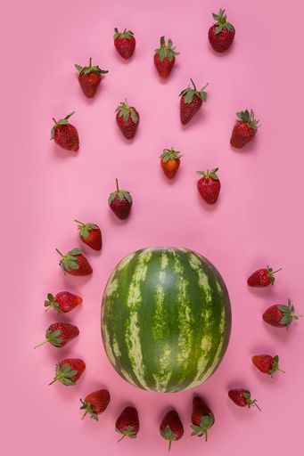 A top view of beautiful composition made of fresh strawberries and watermelon on a pink background
