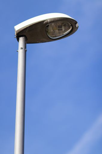 A low angle shot of a gray street light with a clear sunny blue sky in the background