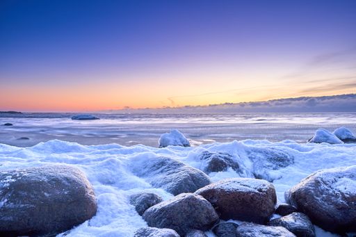 An aerial view of sea waves breaking snow covered beach during sunset