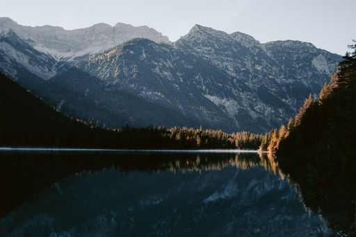 A tranquil lake is framed by an awe-inspiring mountain range in the background, creating an idyllic scene