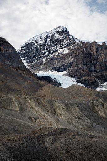 A vertical shot of snowy mountains under a cloudy sky