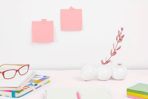 A desktop with office supplies neatly arranged on top and sticky notes in the wall with copy space