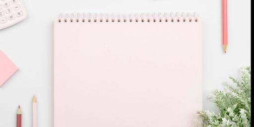 A white office desk with a pink notepad with copy space and pencils arranged on its surface