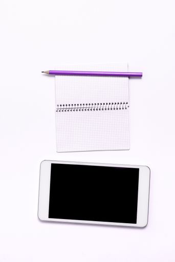 A top view of a smartphone on a white background with a copybook