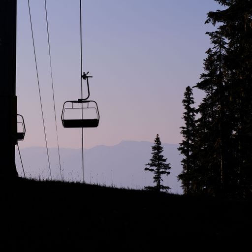 A ski lift chairlift against the backdrop mountain, surrounded by lush evergreen trees