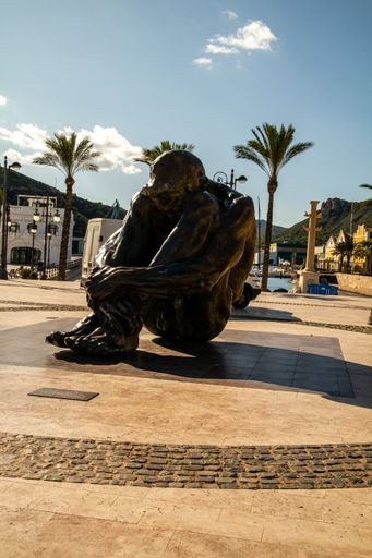 A vertical shot of a beautiful sculpture with palms in the background in Cartagena, Spain
