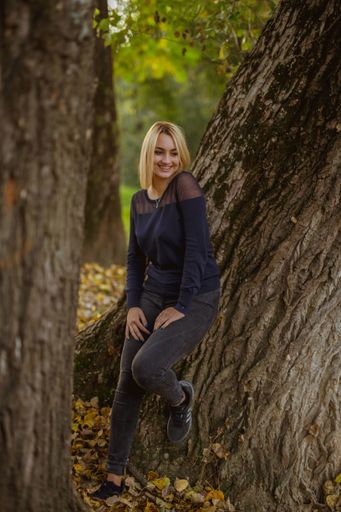 A young blonde lady with black outfit posing for the camera in the autumn park