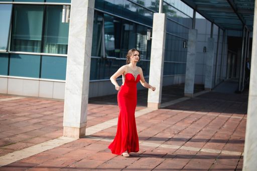 A young attractive lady in an evening red dress posing for the camera