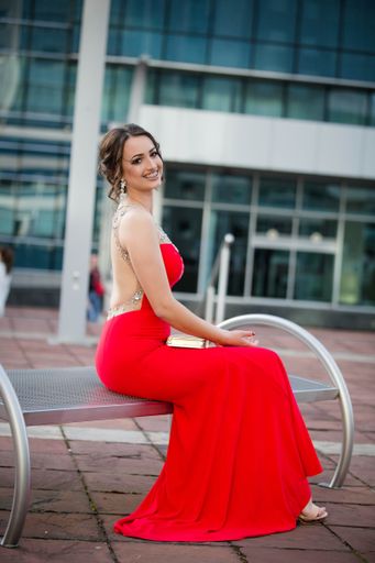 A vertical shot of a beautiful smiling Caucasian woman wearing a sexy long gown posing in a building