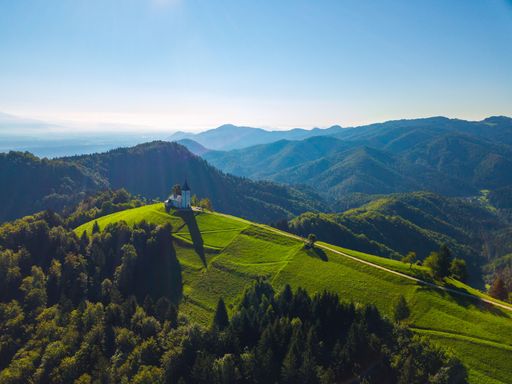 An aerial view of The Church of St. Primoz and Felicijan on the top of lush green hill in Kranj, Slovenia