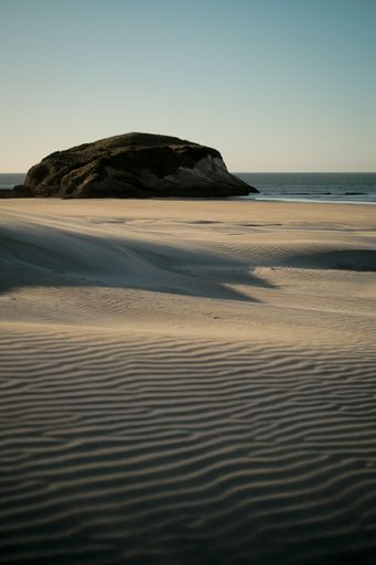 A beautiful shot of the sand blowing across the beach near the ocean
