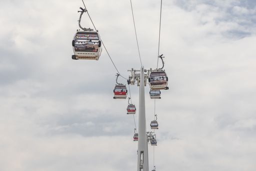 A view of gondola lifts dangling from the side of a cable in a mountainous area
