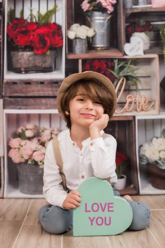 This is a charming little boy sitting on the floor with a sign that says "I love you