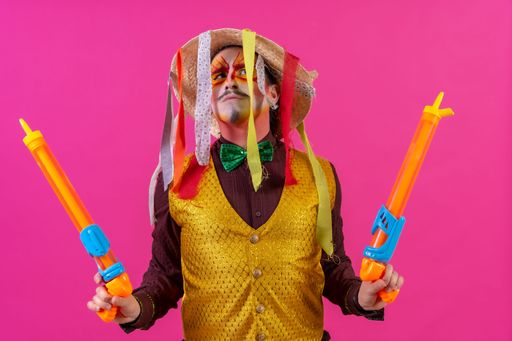 A cheerful circus performer with a sombrero holding toy water guns on pink background
