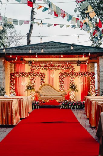 A wedding stage decorated in red and gold with white garlands