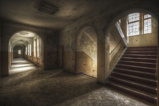 A beautiful shot of a hallway with stairs and windows in an old building