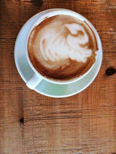 A top view of a cup of cappuccino coffee on a wooden table