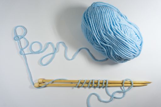 A blue yarn ball with knitting needles on white background