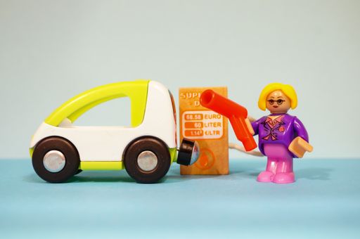 Playtive toy wo figurine tanking a car next to pump on a blue soft focus background.