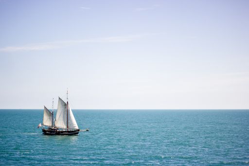 A sailing boat with white sails on a calm sea surface at daytime
