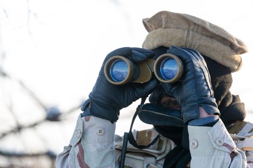 A shallow focus shot of a soldier looking through binoculars