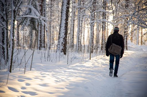 An unrecognizable man walking through a path in the park fully covered with snow in winter