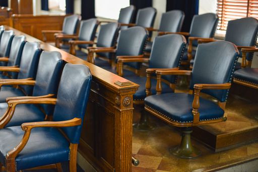 An empty jury box with blue leather chairs and windows in the background