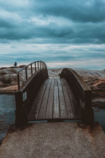 This beautiful photo shows a wooden bridge leading to an ocean under a dark sky