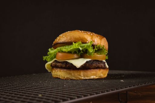 Close-up of a freshly grilled hamburger topped with lettuce and tomato slices, served on a toasted bun