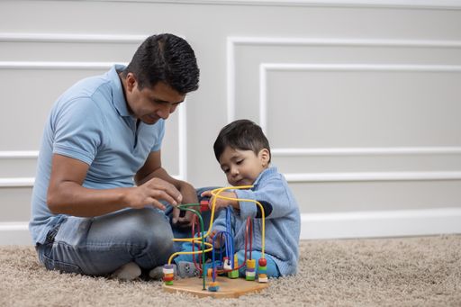 Mexican father and son playing on the carpet at home